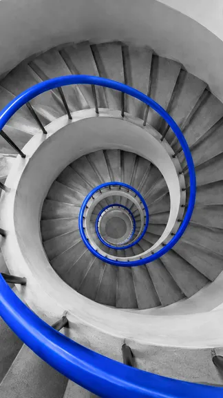 Spiral staircase from above with a blue handrail