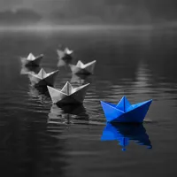 Paper boats led by a blue boat