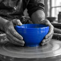 Potter's hands shaping a blue bowl